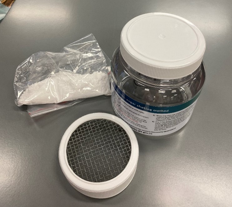 Image of equipment used to make a shake jar. Equipment includes jar, solid and mesh lids and icing sugar in a plastic bag.
