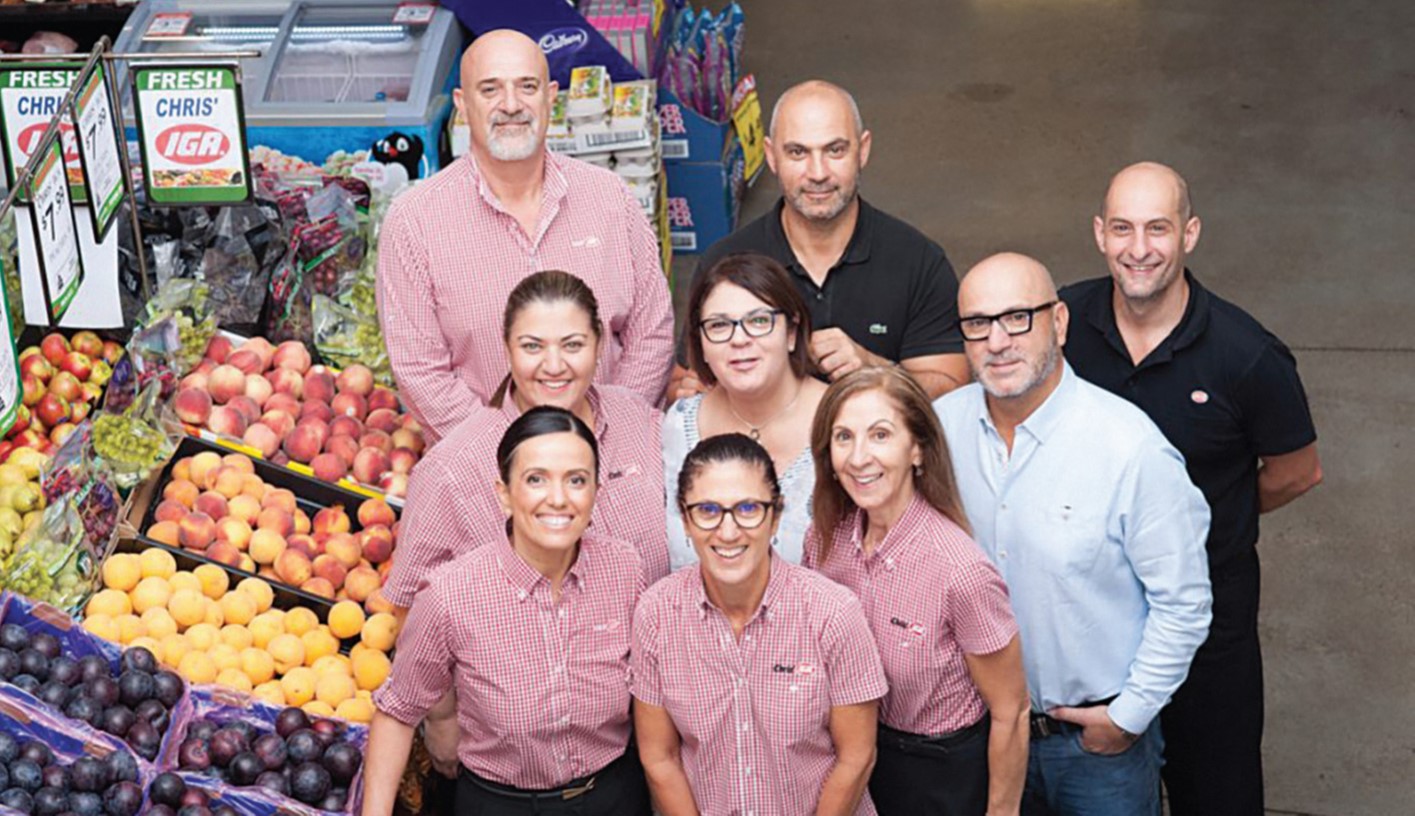 Group of workers from Chris' IGA store standing beside a fresh fruit display.